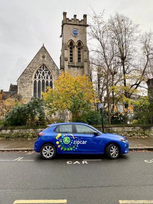 a blue car parked in front of a church